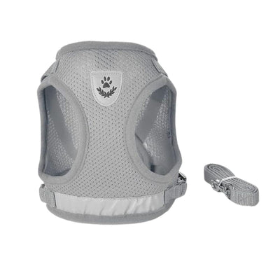 A light gray mesh dog harness with a matching adjustable strap, shown on a plain white background. The harness features a central shield-shaped patch with a dark gray paw print and leaf design.